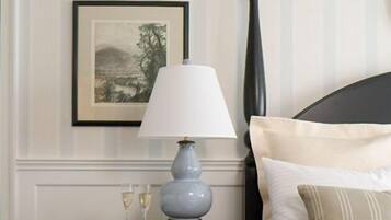 A neatly arranged bedroom with a bed, a bedside table with a lamp, and a framed picture on the wall.