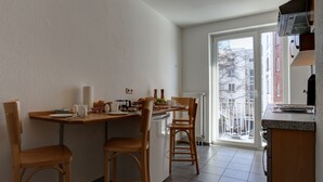 Una cocina pequeña con una mesa de comedor, dos sillas de madera y un refrigerador.