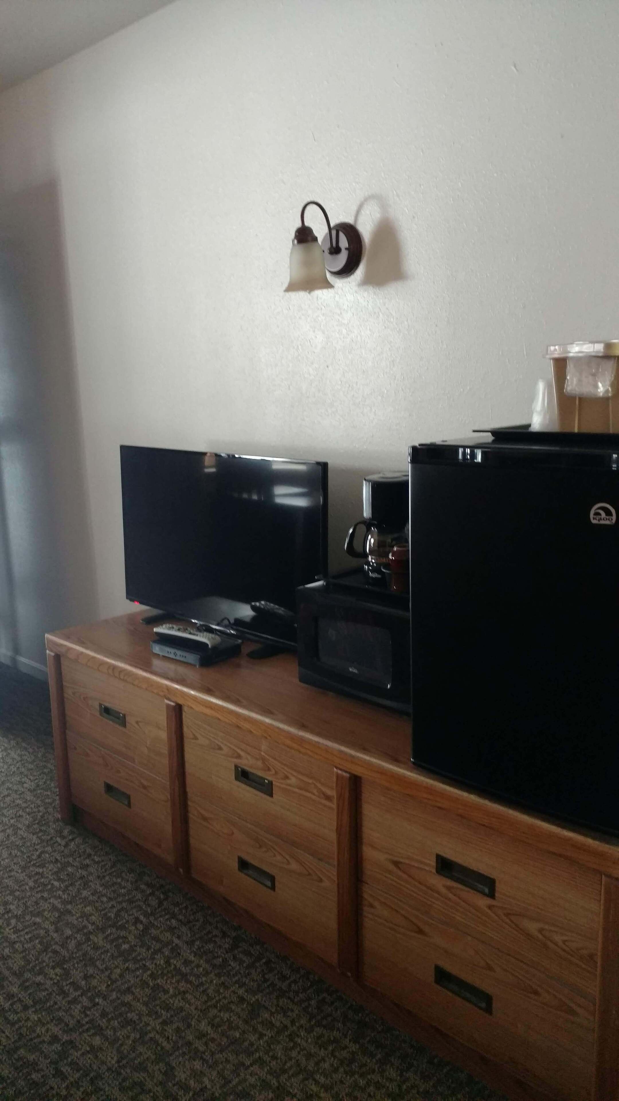 Ein Holzkabinett mit einem Flachbildfernseher, einer Kaffeemaschine und einem Kühlschrank.