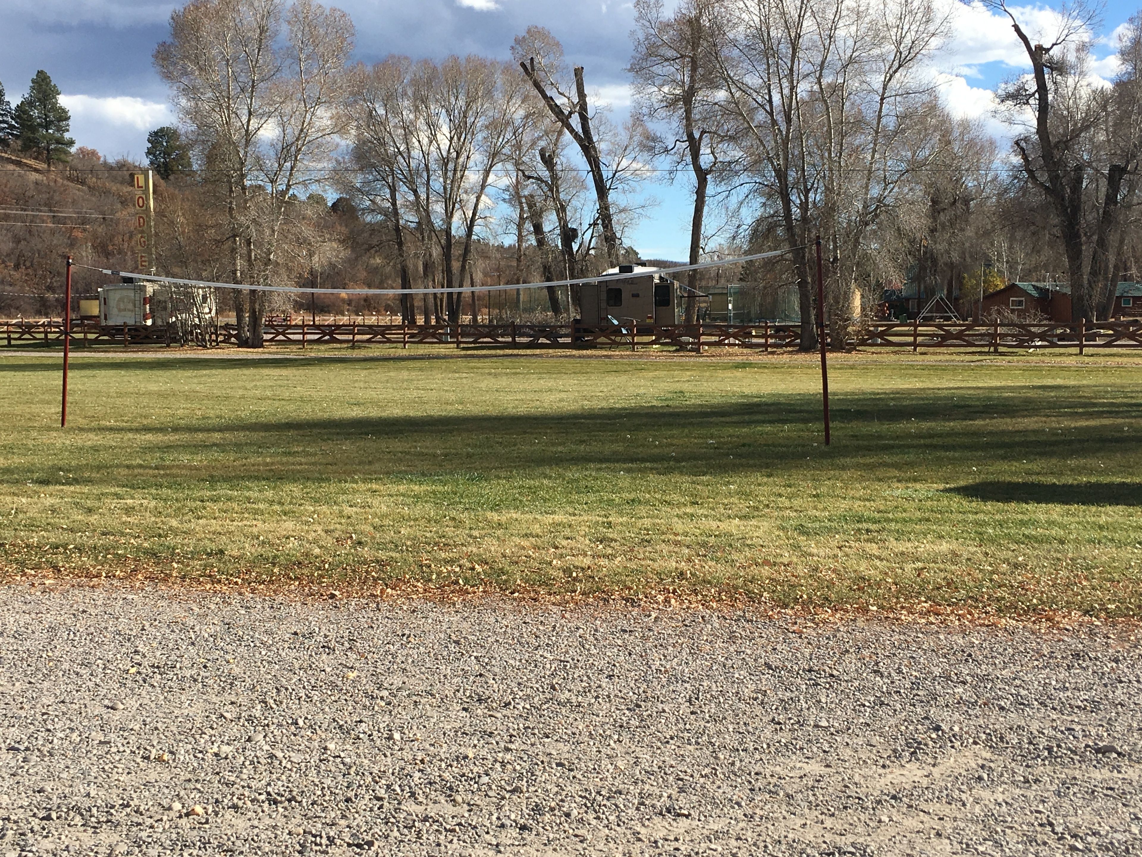 A gravel path leading to a grassy area with a volleyball net.