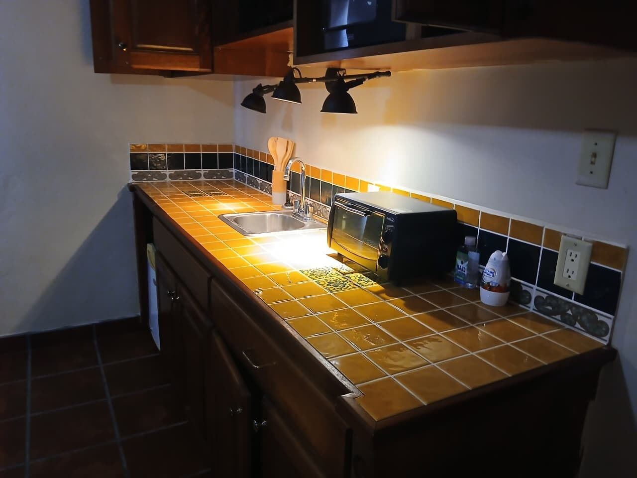Una cocina con salpicadero de azulejos, un lavabo, un tostador y armarios.