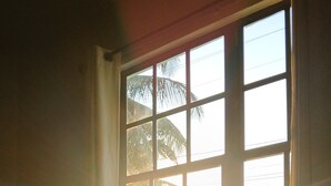 Una habitación con cama, ventana y vista a palmeras.