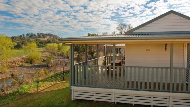 A single-story house with a porch, a small deck, and a view of a river and hills.
