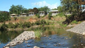A row of cabins with a river in the foreground.