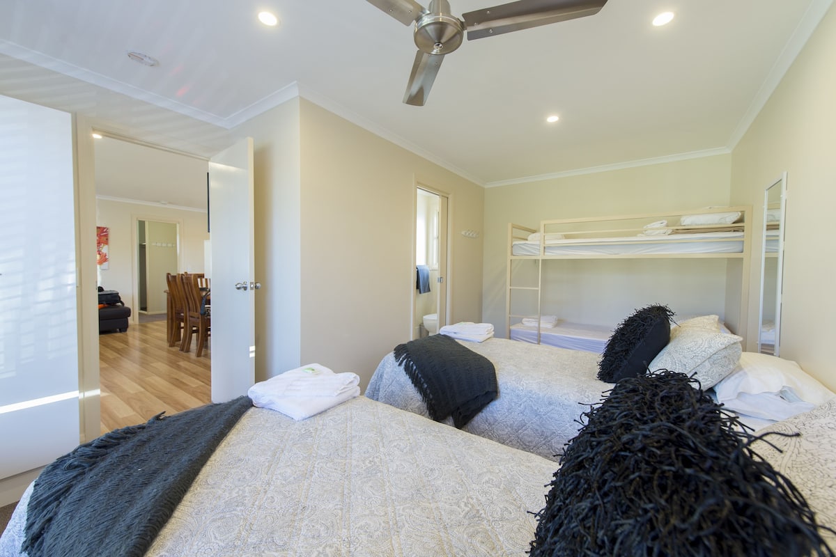 A bedroom with two beds, a ceiling fan, and a bunk bed.