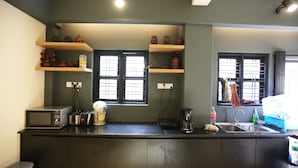 Une cuisine avec des meubles de couleur sombre, un four à micro-ondes, un grille-pain, une machine à café et un évier.