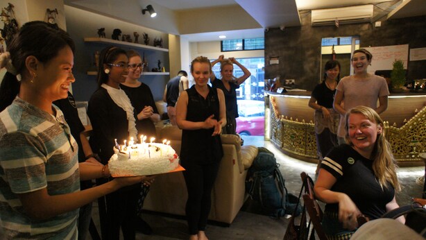 Un groupe de personnes s’est rassemblé autour d’un gâteau orné de bougies allumées, ce qui laisse supposer qu’il s’agit d’une célébration ou d’un événement.