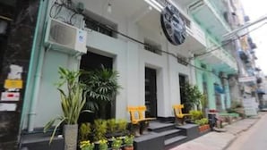 Un bâtiment à la façade blanche, doté de nombreuses portes et orné de plantes en pot au rez-de-chaussée.