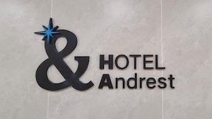 Schild für ein Hotel namens 'Andrest' mit einem markanten Logo, das ein stilisierter Doppelstrich und ein blauer Stern sind.