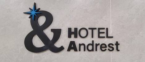 A sign for a hotel named "Andrest" with a distinctive logo featuring a stylized ampersand and a blue star.