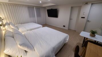 Ein Hotelzimmer mit zwei Betten, einem an der Wand montierten Fernseher, einem Schreibtisch mit Pflanze und einer Tür mit der Beschriftung '603 HOTEL Andrest'.