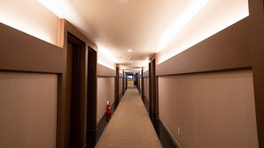 A long, well-lit hallway with a carpeted floor, leading to a door at the end. - Hotel Prime Changwon (Changwon)