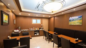 A dining area with a wooden table and chairs, a buffet station, and a ceiling light fixture. - Hotel Prime Changwon (Changwon)