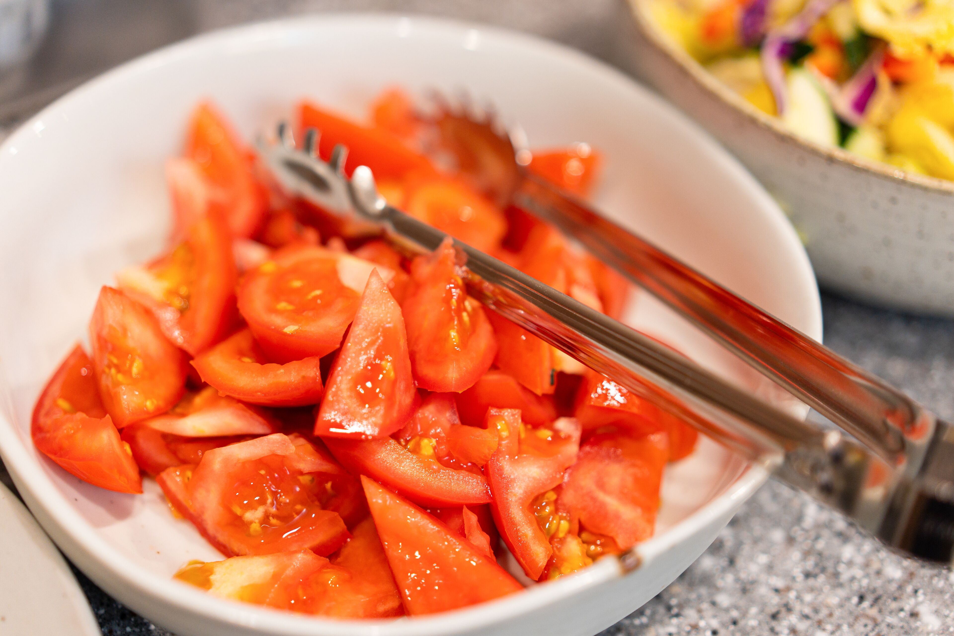 A bowl of sliced tomatoes with a fork and knife.