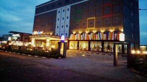 A multi-story hotel with a central courtyard, featuring a neon sign and a series of balconies.
