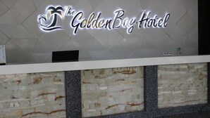 A reception desk with a sign that reads "The Golden Bay Hotel."