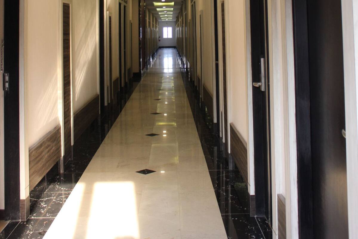 A long, narrow hotel corridor with a polished floor, recessed lighting, and doors on both sides.