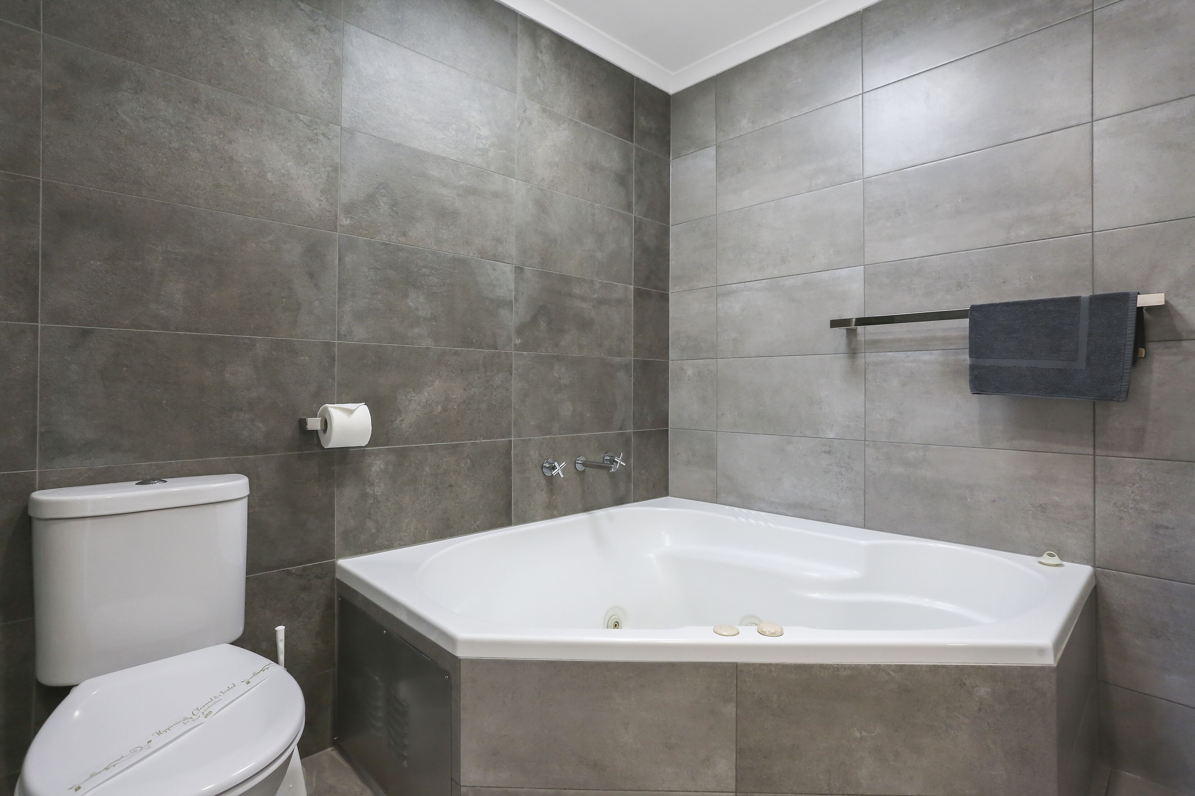 Un baño con bañera, inodoro y toallero.