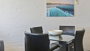 A dining area with a glass table, black chairs, and a white bowl. - Crown Apartments (Merimbula)