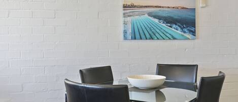 A dining area with a glass table, black chairs, and a white bowl.