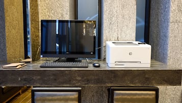 Una mesa de recepción con computadora de escritorio, impresora HP y teclado.