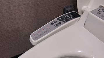 A modern toilet with a control panel featuring buttons for bidet functions, water temperature, and nozzle position.