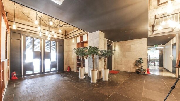 A spacious lobby with a modern design, featuring a large entrance with glass doors, potted plants, and a tiled floor. - Chuncheon Urbane Hotel (Chuncheon)