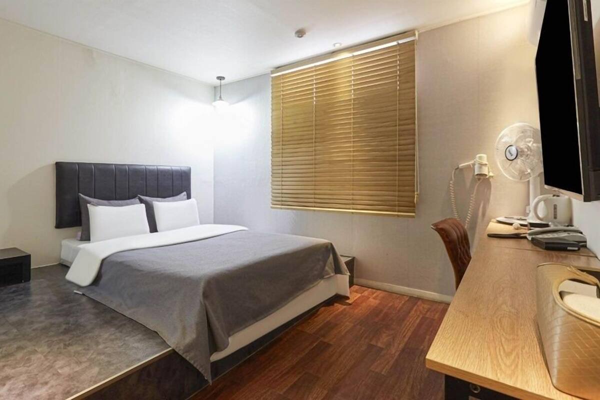 A modern bedroom with a bed, bedside table, and a desk with a chair.