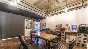 A dining area with a wooden table and black leather chairs, a refrigerator, and a coffee machine. - Chuncheon Urbane Hotel (Chuncheon)
