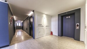 A long, narrow hallway with a polished floor, white doors, and a fire extinguisher on the right. - Chuncheon Urbane Hotel (Chuncheon)