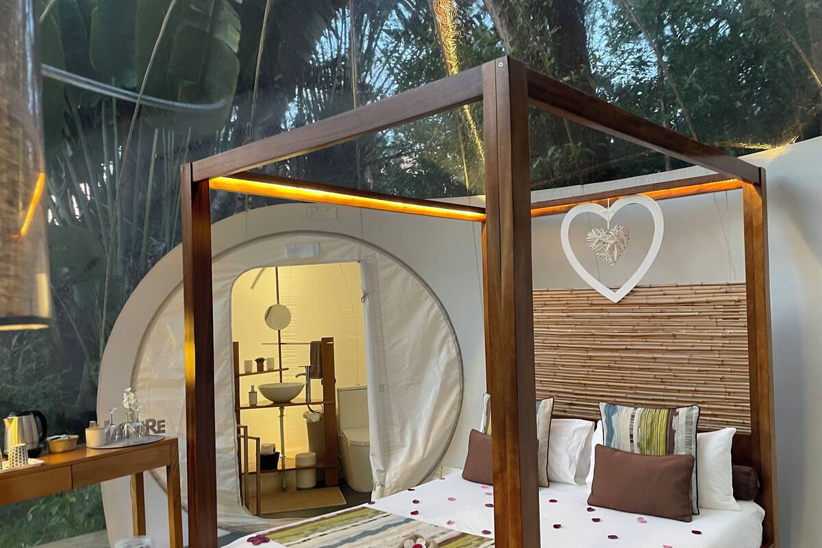 A tent-style room with a bed, a small table, and a mirror.