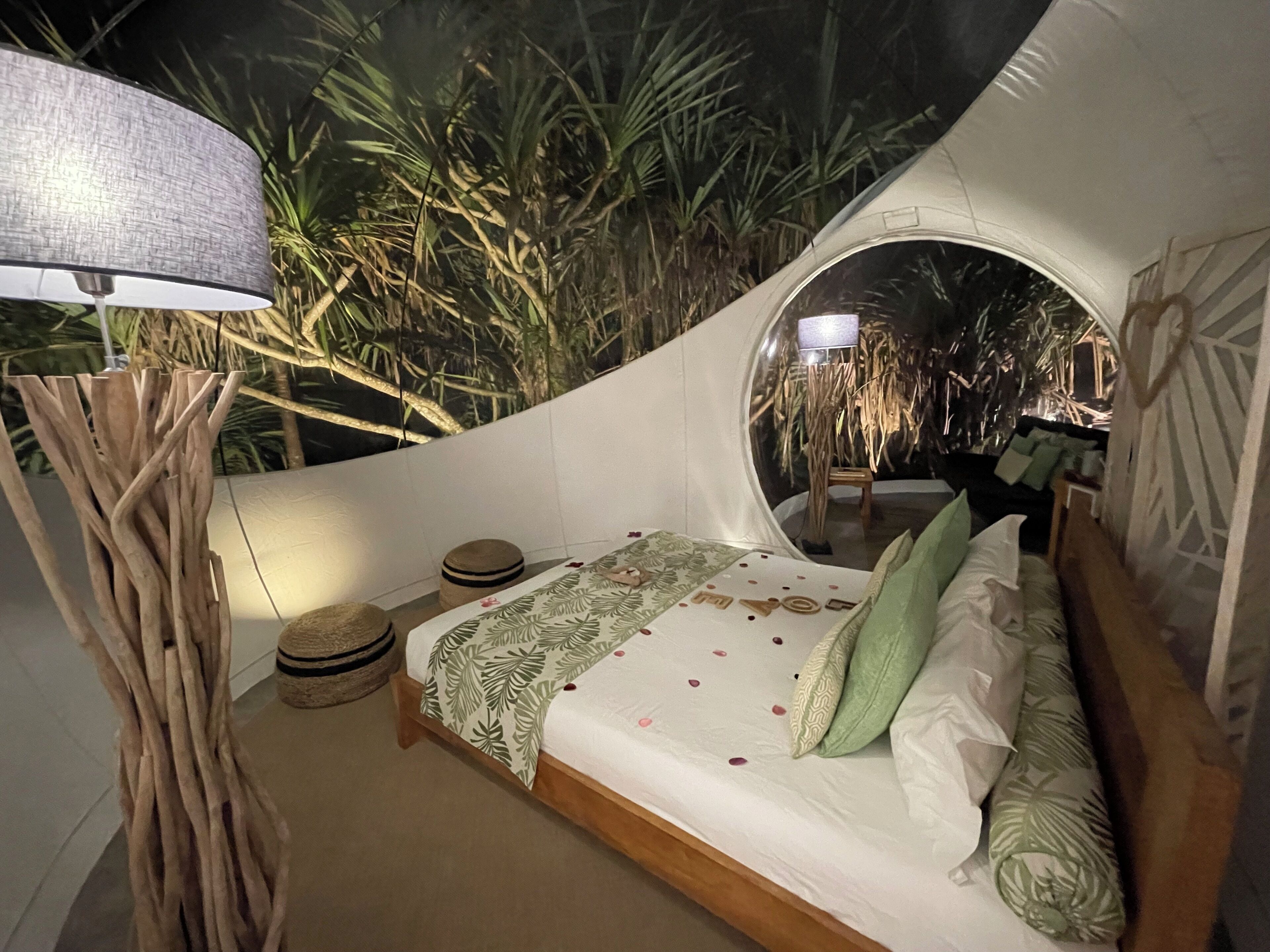 A circular tent-style room with a bed, a lamp, and a small stool.