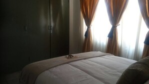 Un dormitorio con cama, armario y cortinas.