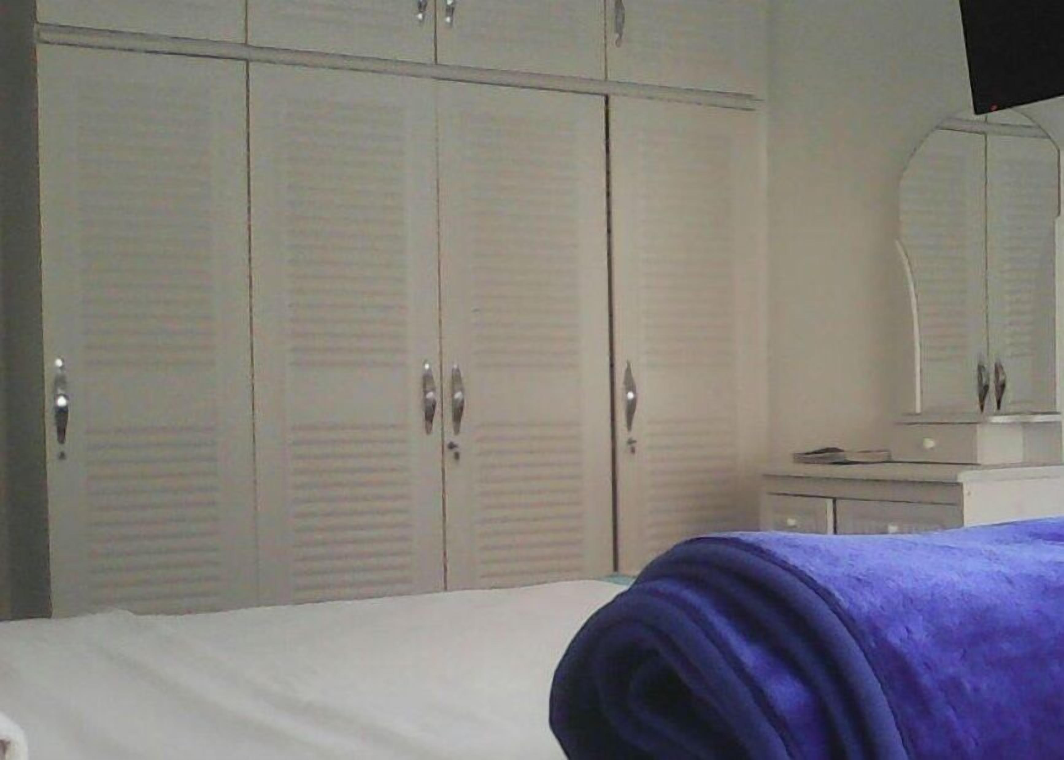 A bedroom with a bed, a dresser, a mirror, and a wardrobe.