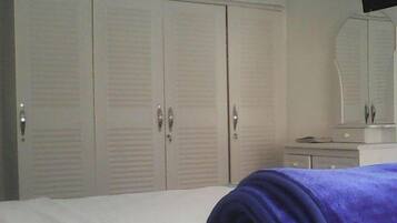 A bedroom with a bed, a dresser, a mirror, and a wardrobe.