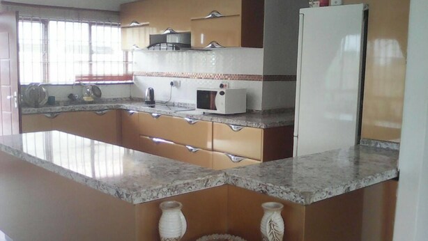 Una cocina con encimera de granito, microondas, tostadora y refrigerador.