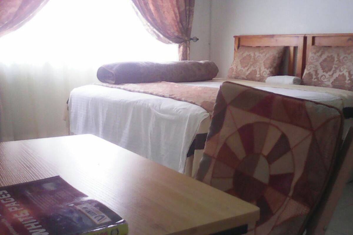 Ein Hotelzimmer mit Bett, Stuhl, Tisch und einem fensterbepflanzten Fenster.