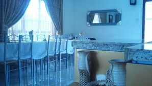 Un comedor con una mesa dispuesta para cuatro personas, sillas, un florero y un espejo en la pared.