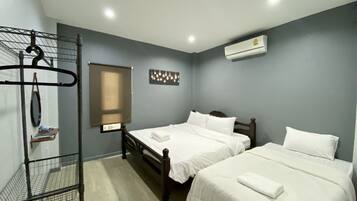 A hotel room with two beds, a metal rack, a window with blinds, and an air conditioning unit.