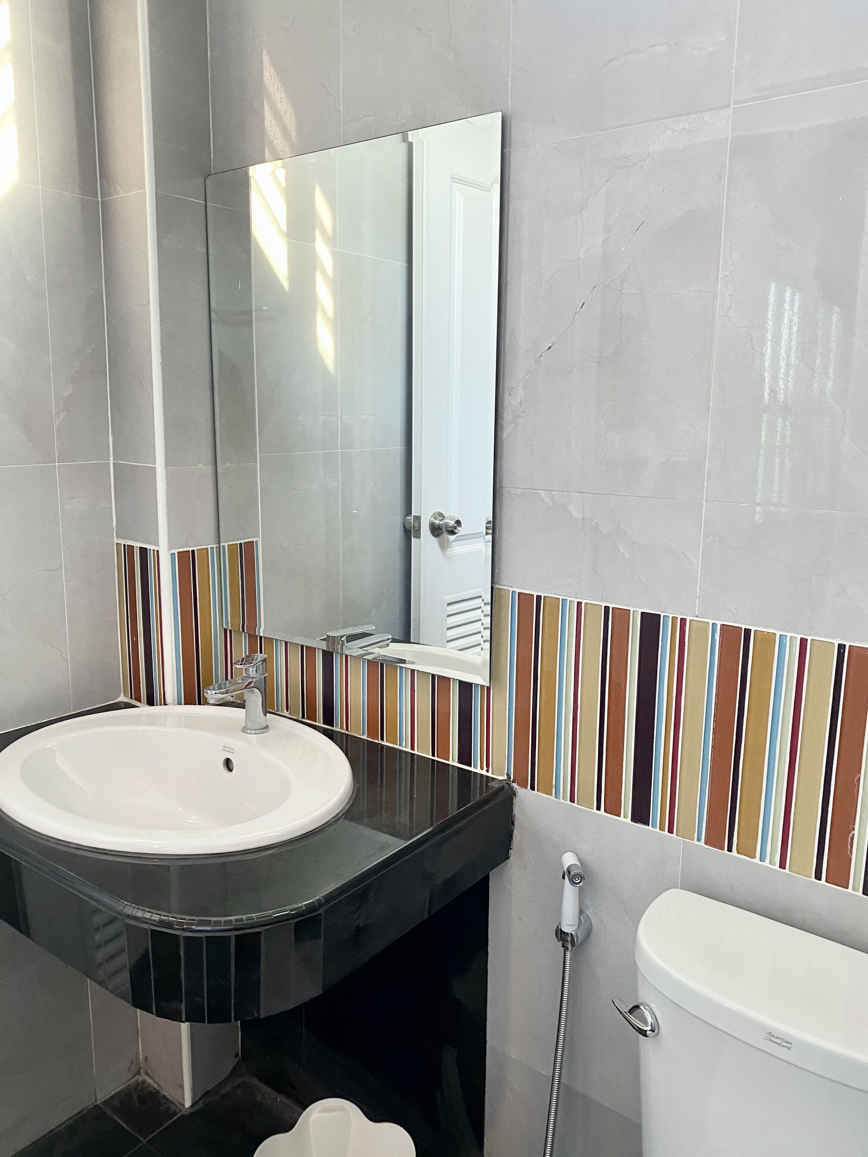 Une salle de bain avec un lavabo blanc, un plan de toilette noir et des toilettes.