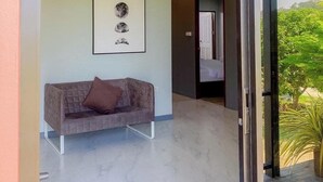 A modern interior with a marble floor, a grey sofa with a brown cushion, and a framed lunar phase display on the wall. - Maerim Villa & Pool (Mae Rim)