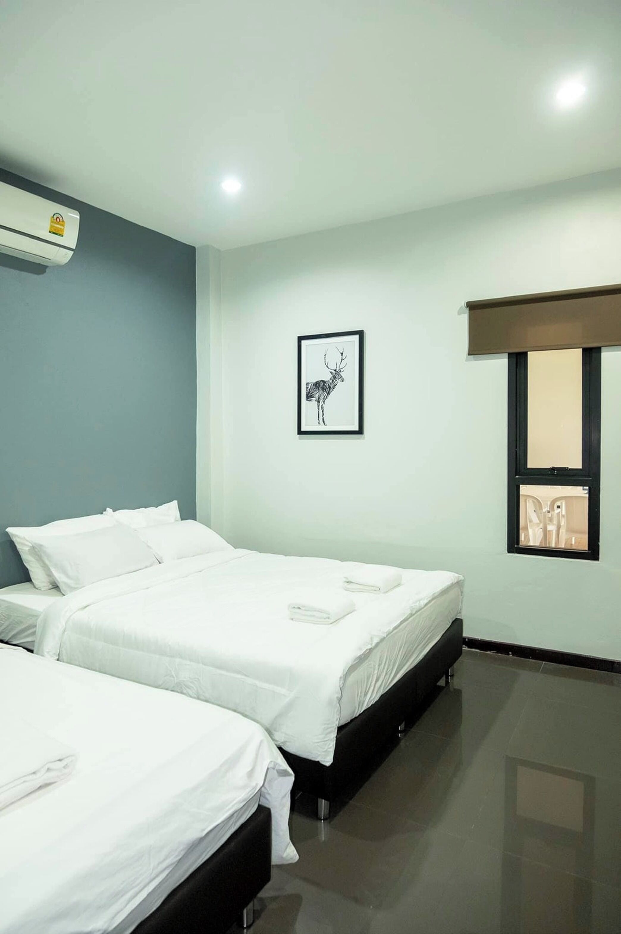 A hotel room with two beds, a framed picture on the wall, and an air conditioning unit.