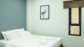 A hotel room with two beds, a framed picture on the wall, and an air conditioning unit.