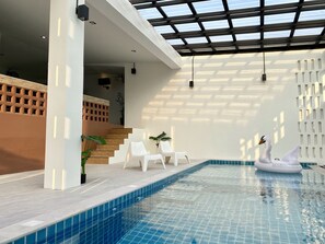 An indoor swimming pool with clear blue tiles, white chairs, and a swan inflatable on the edge. - Maerim Villa & Pool (Mae Rim)