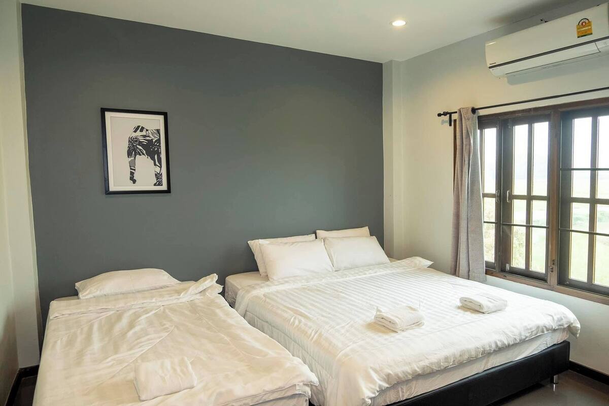A hotel room with two beds, a framed picture on the wall, and an air conditioning unit.