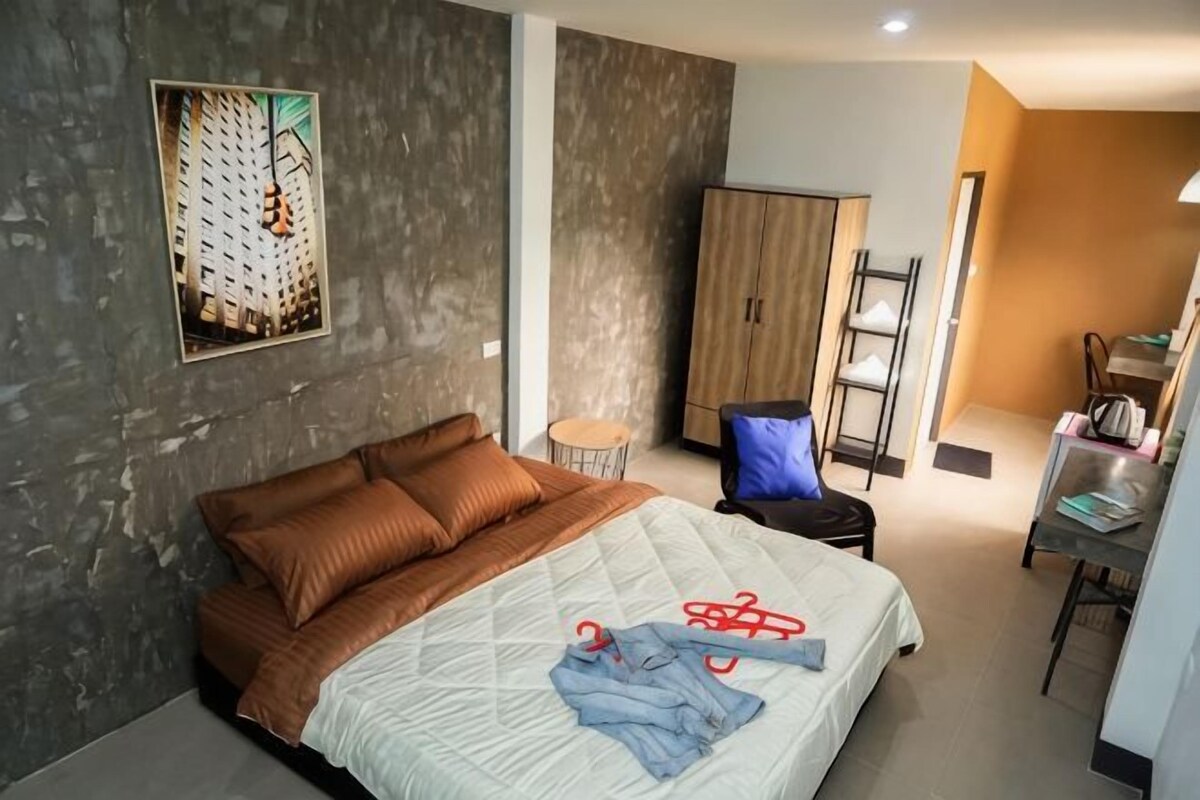 Una habitación de hotel moderna con una cama grande, un armario, un escritorio y una silla.