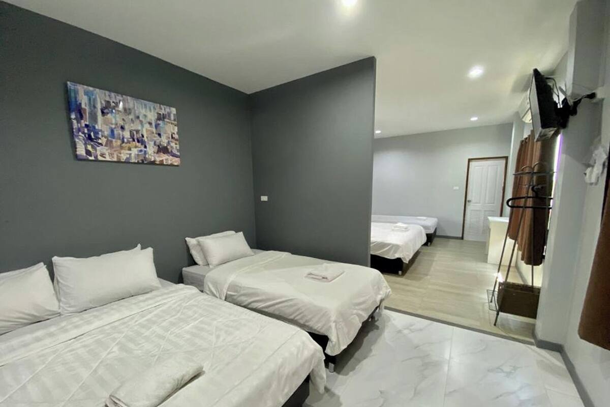 A hotel room with two beds, a painting on the wall, and a mirror reflecting another room.