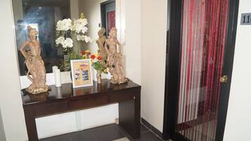 A reception desk with two statues, a vase of flowers, and a framed picture.