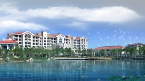 Un hotel grande con varias edificaciones, una masa de agua al frente y un cielo despejado.