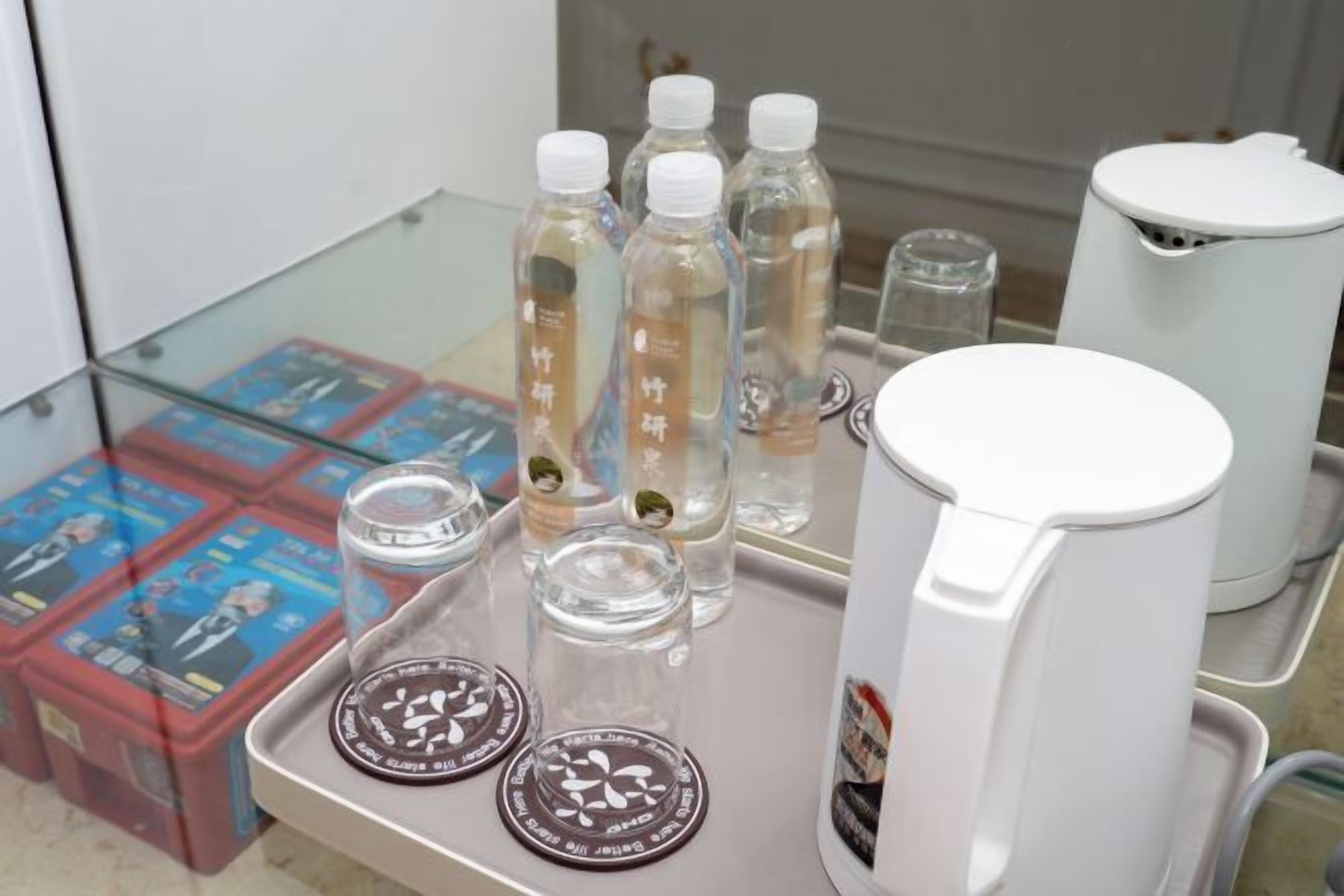 A tray with bottles, glasses, and a coffee maker on a table.